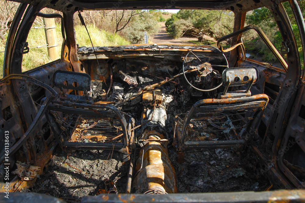 A burnt out car on a country road near a creek A burnt out car on a country road near a creek
