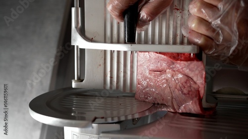 Photography Butcher slicing meat with professional slicer machine