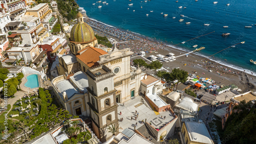 Aerial view of the collegiate church of Positano in the province of Salerno, Campania, Italy. This church is dedicated to Santa Maria Assunta and is near the beach, overlooking the Mediterranean Sea.