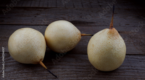 Three pears are lying on a wooden board. Snow pear.