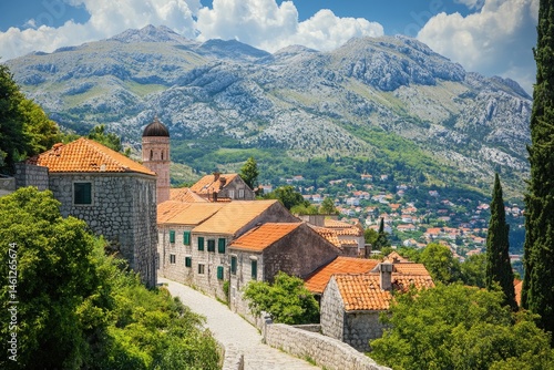 Obraz na płótnie Picturesque hillside village nestled amid towering mountains under a vibrant blue sky w salonie