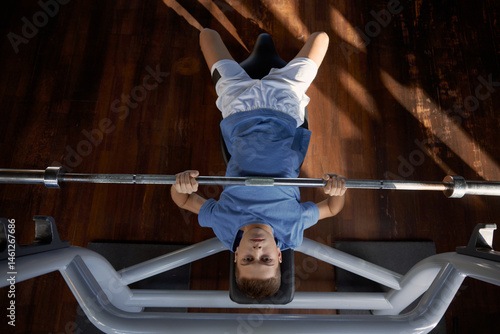 Obraz na płótnie Teenager lifting heavy barbell doing bench press exercise at gym w salonie