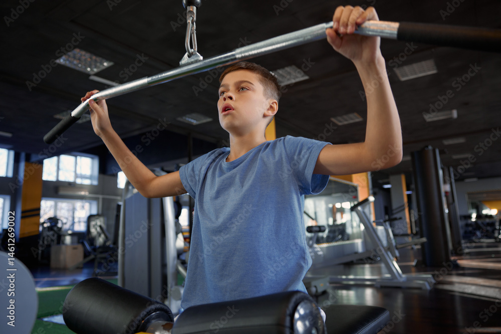 Inspired teenage boy enjoying training on modern gym sports equipment