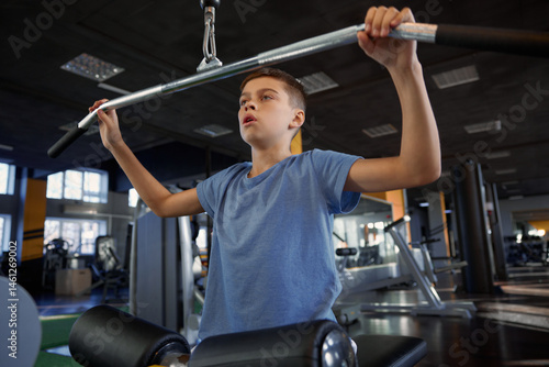 Obraz na płótnie Inspired teenage boy enjoying training on modern gym sports equipment w salonie