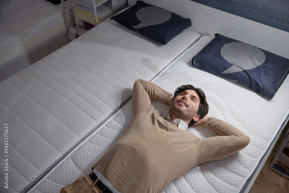 Man checking a stylish mattress visiting a furniture showroom, showcasing ultimate comfort