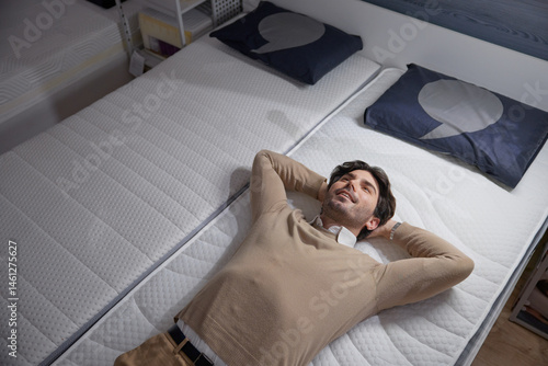 Obraz na płótnie Man checking a stylish mattress visiting a furniture showroom, showcasing ultimate comfort w salonie