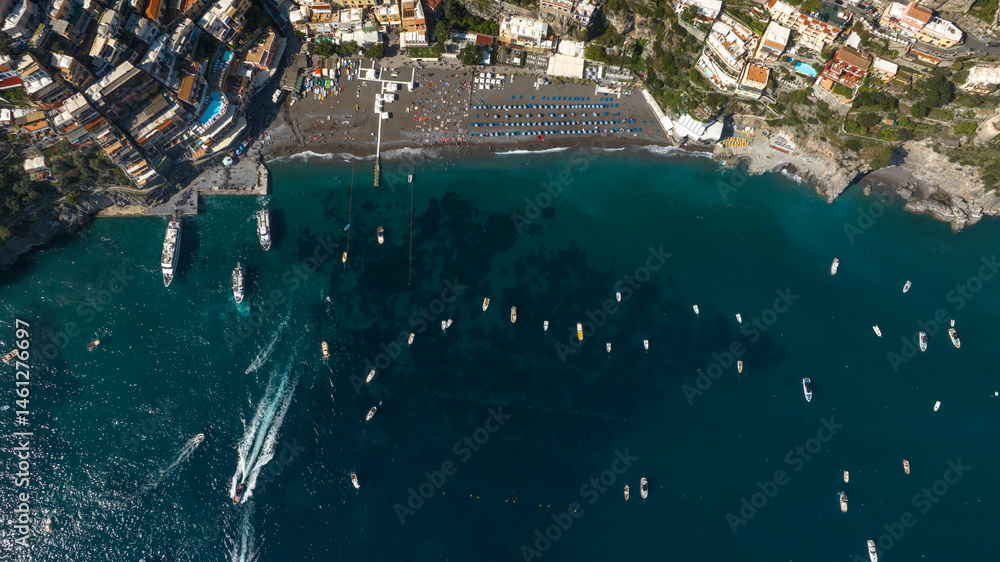 Perpendicular aerial view of the beach of Positano in the province of Salerno, Campania, Italy. There are umbrellas on the sand and people on vacation at sea.
