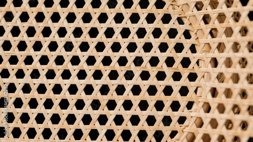 A wooden chair with a pattern of triangles on it. The chair is made of woven wood and has a brown color. The pattern of the triangles is quite intricate and adds a unique touch to the chair