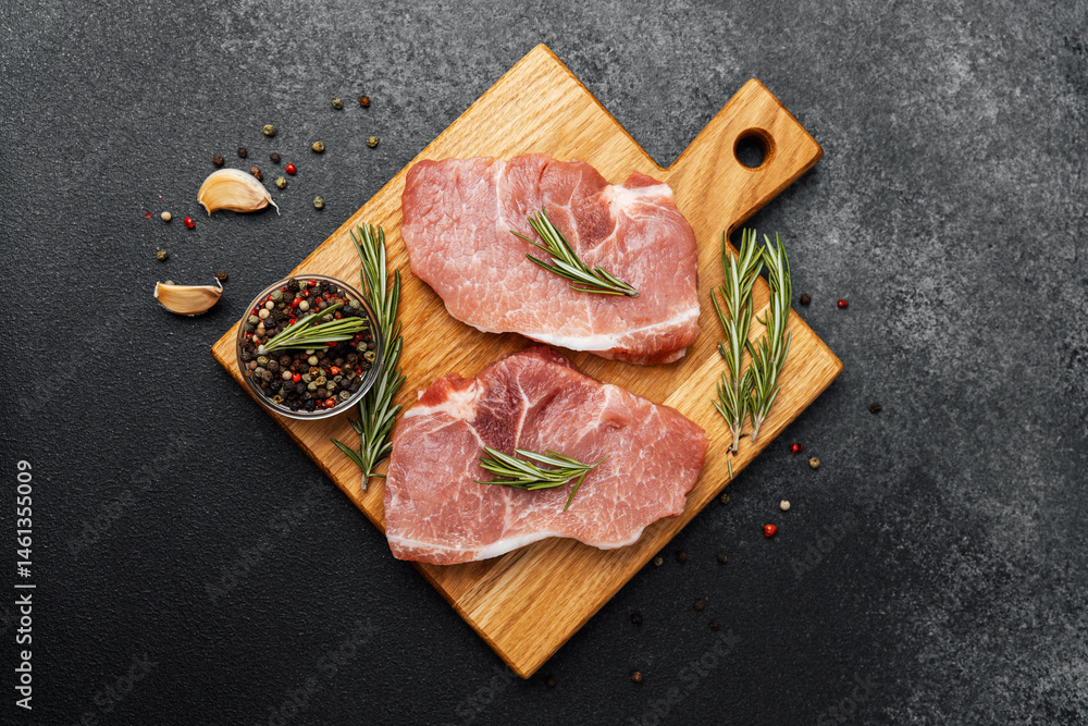 Fresh pork chops prepared with herbs and spices on a wooden cutting board