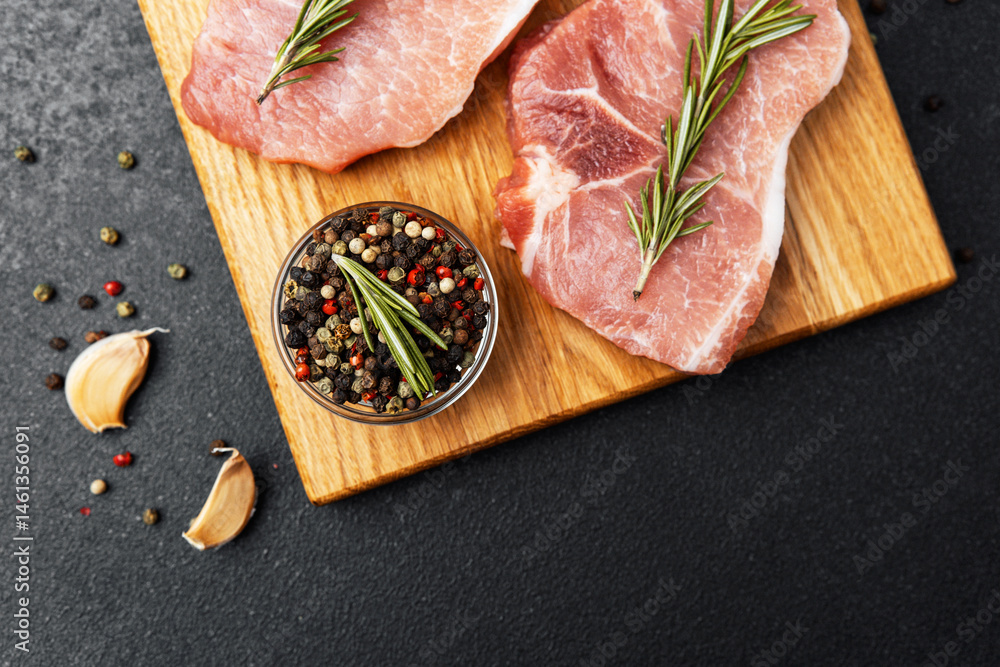Freshly prepared pork chops with herbs and spices on a wooden cutting board
