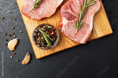 Obraz na płótnie Freshly prepared pork chops with herbs and spices on a wooden cutting board w salonie