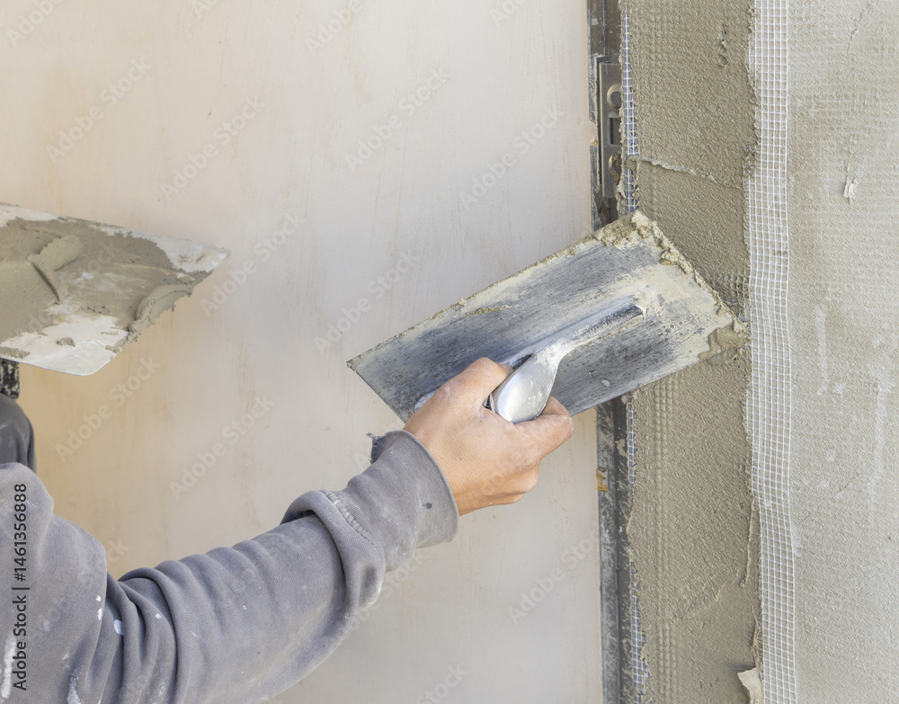 Craftsman uses a float trowel and cement to plaster a house wall. Construction process