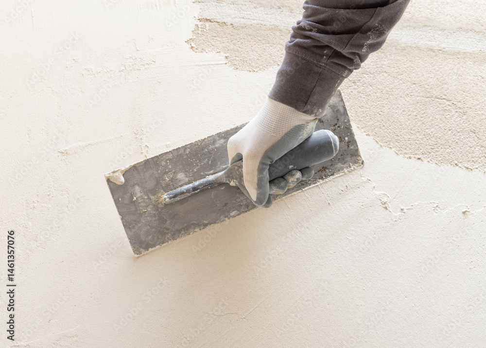 Craftsman uses a float trowel and cement to plaster a house wall. Construction process