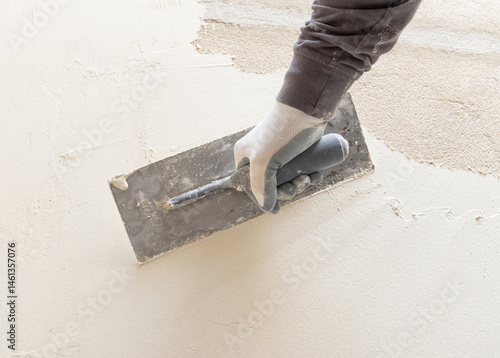 Obraz na płótnie Craftsman uses a float trowel and cement to plaster a house wall. Construction process w salonie