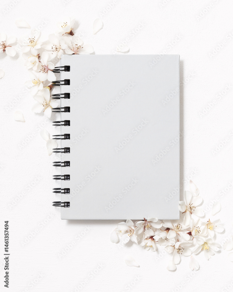 Gray blank spiral notebook near white cherry flowers top view, spring wedding mockup