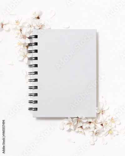 Obraz na płótnie Gray blank spiral notebook near white cherry flowers top view, spring wedding mockup w salonie
