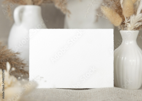 Blank card near dry beige pampas grass on linen closeup, mockup. Bohemian wedding stationery
