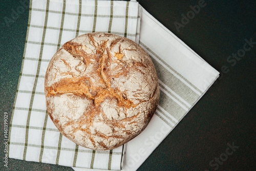 Obraz na płótnie Rustic sourdough bread resting on a striped kitchen towel in a cozy kitchen w salonie