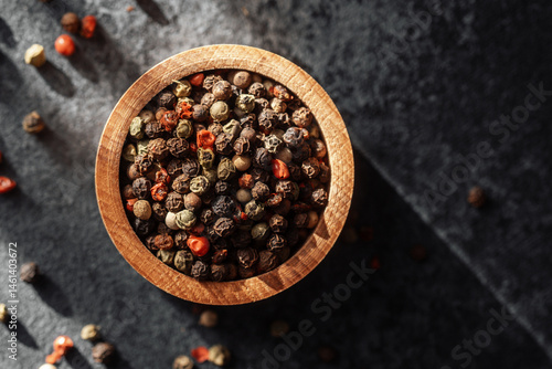 Obraz na płótnie Colorful peppercorns in a wooden bowl on a dark surface with natural light w salonie