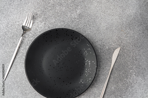 Obraz na płótnie Elegant black plate with silver cutlery on a textured gray surface w salonie