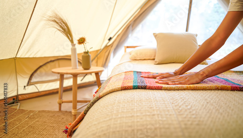 Woman Making Bed in Cozy Glamping Tent: Colorful Blanket & Rustic Decor. Preparing for Relaxing Outdoor Getaway & Hygge Lifestyle, 4K.