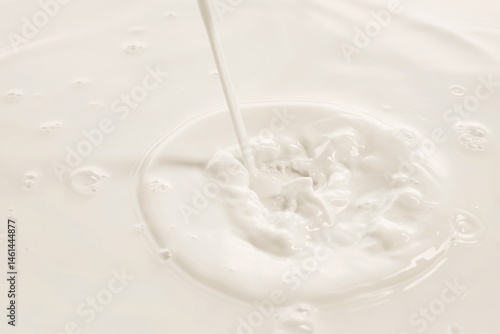 Obraz na płótnie Milk stream hits white liquid creating splash and swirl in soft lighting. Concept of drink, organic food, aesthetics, advertisement w salonie