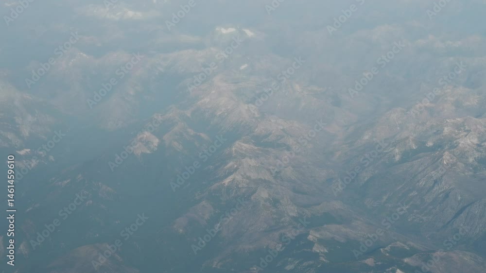 High-altitude drone shot showcasing rugged mountain terrain under a soft blue sky, layered with light atmospheric haze High-altitude drone shot showcasing rugged mountain terrain under a soft blue sky, layered with light atmospheric haze