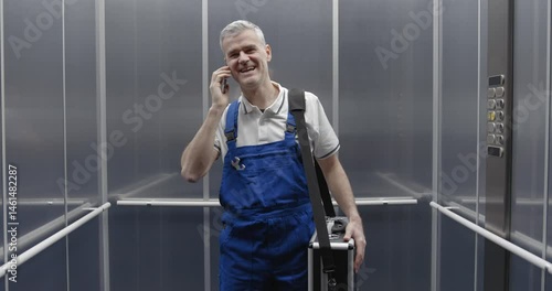 Professional technician having a phone call in the elevator