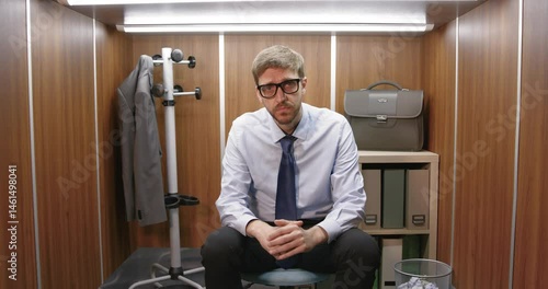 Sad frustrated businessman sitting in a small office
