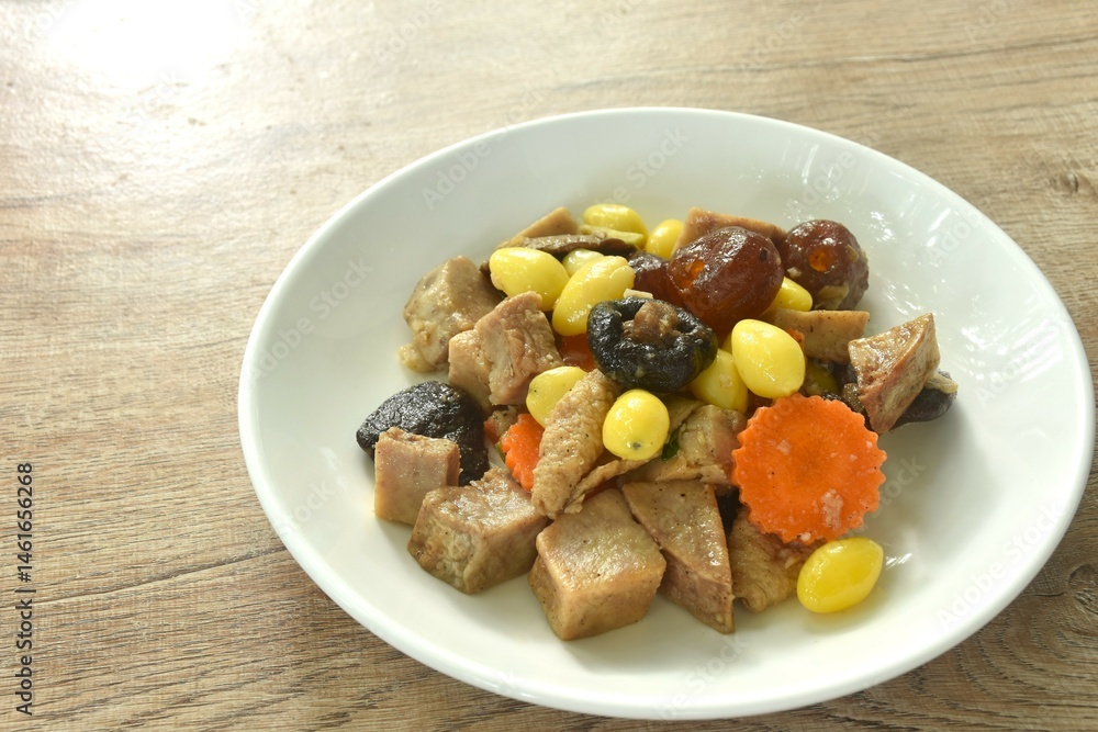 deep fried tofu and gluten with yellow ginkgo and pickled jujube couple black mushroom in soy sauce vegetarian food on plate
