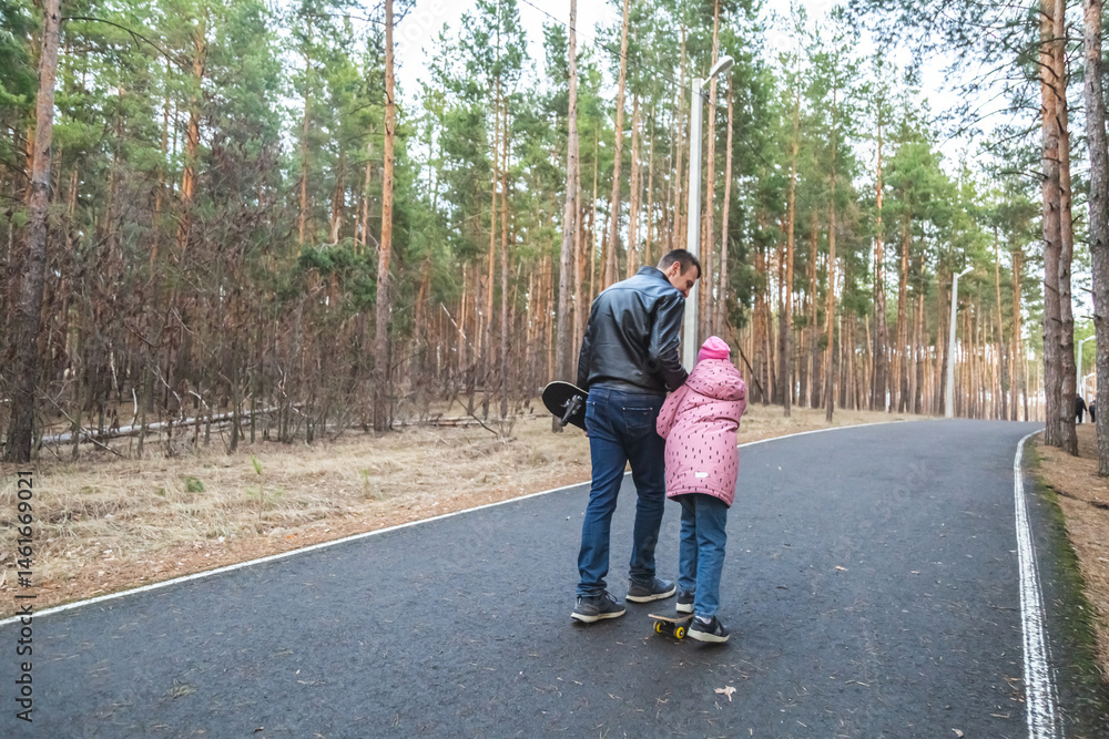Fototapeta premium Father and daughter riding skateboards in the forest.