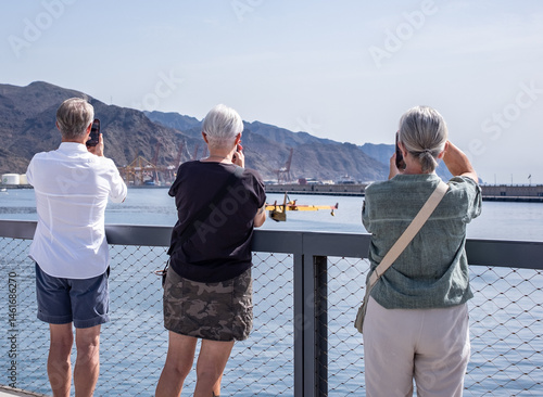Картината върху платно A group of three people film with their cell phones a Canadair plane while it lo