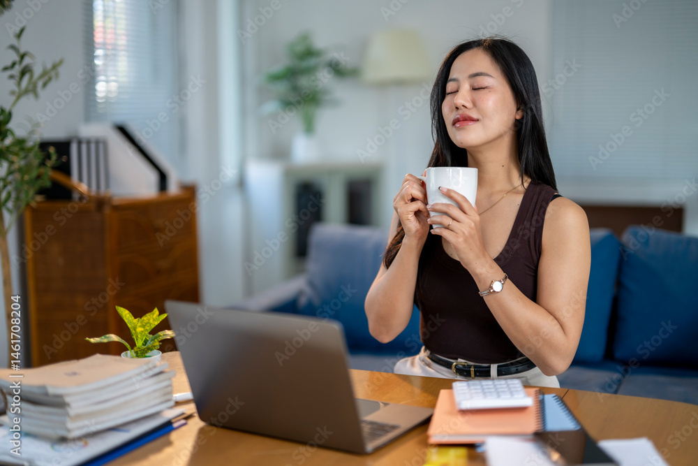 A woman is sitting at a desk with a laptop and a cup of coffee A woman is sitting at a desk with a laptop and a cup of coffee