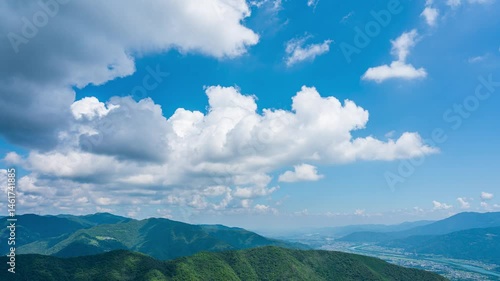 タイムラプス　青空に流れるたくさんの白い雲と、緑に包まれた山々