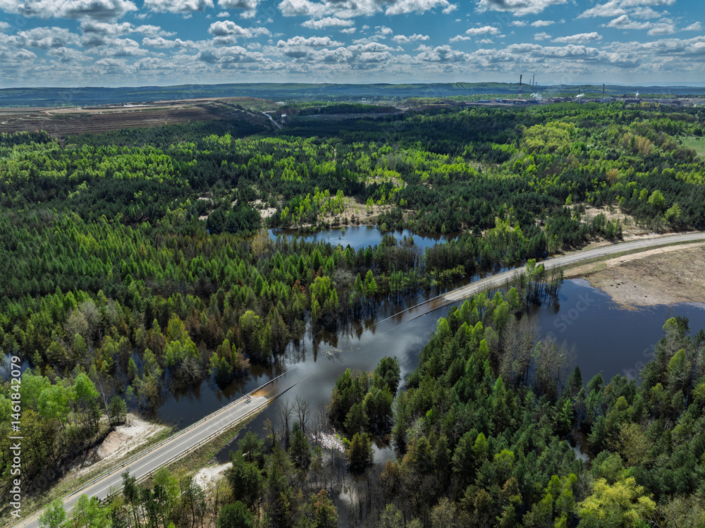 Lake District swallow hole flooded as a result of the mining damage Pomorzany mine in Olkusz,Poland. Aerial drone view of flooded road. Forest submerged in a lake. Sunken sandpit with clear water