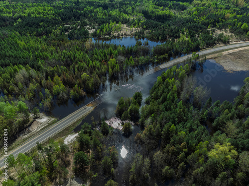 Obraz na płótnie Lake District swallow hole flooded as a result of the mining damage Pomorzany mine in Olkusz,Poland. Aerial drone view of flooded road. Forest submerged in a lake. Sunken sandpit with clear water w salonie