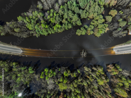 Obraz na płótnie Lake District swallow hole flooded as a result of the mining damage Pomorzany mine in Olkusz,Poland. Aerial drone view of flooded road. Forest submerged in a lake. Sunken sandpit with clear water w salonie