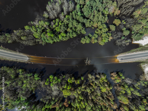 Obraz na płótnie Lake District swallow hole flooded as a result of the mining damage Pomorzany mine in Olkusz,Poland. Aerial drone view of flooded road. Forest submerged in a lake. Sunken sandpit with clear water w salonie