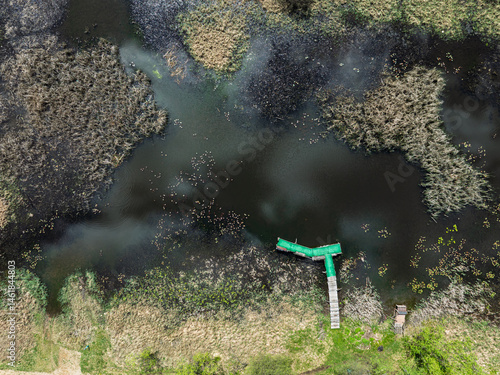 Obraz na płótnie Lake District swallow hole flooded as a result of the mining damage Pomorzany mine in Olkusz,Poland. Aerial drone view of flooded road. Forest submerged in a lake. Sunken sandpit with clear water w salonie