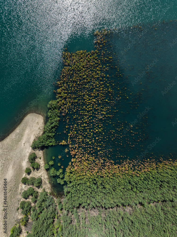 Lake District swallow hole flooded as a result of the mining damage Pomorzany mine in Olkusz,Poland. Aerial drone view of flooded sand pit. Forest submerged in a lake. Sunken sandpit with clear water