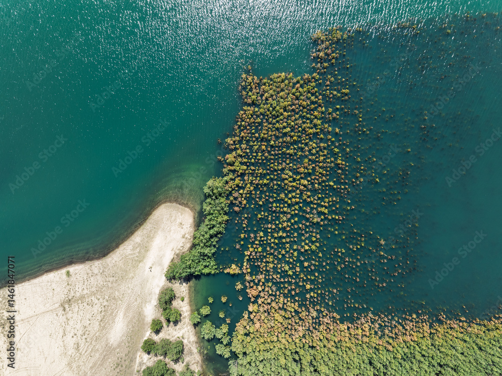 Lake District swallow hole flooded as a result of the mining damage Pomorzany mine in Olkusz,Poland. Aerial drone view of flooded sand pit. Forest submerged in a lake. Sunken sandpit with clear water