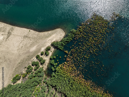 Lake District  swallow hole flooded as a result of the mining damage Pomorzany mine in Olkusz,Poland. Aerial drone view of flooded sand pit. Forest submerged in a lake. Sunken sandpit with clear water