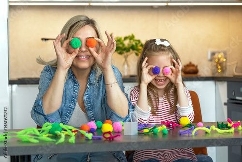 Happy family mother and little daughter fun create craft from colored chenille wire toys play and laugh. Diy. Leisure with children. Education