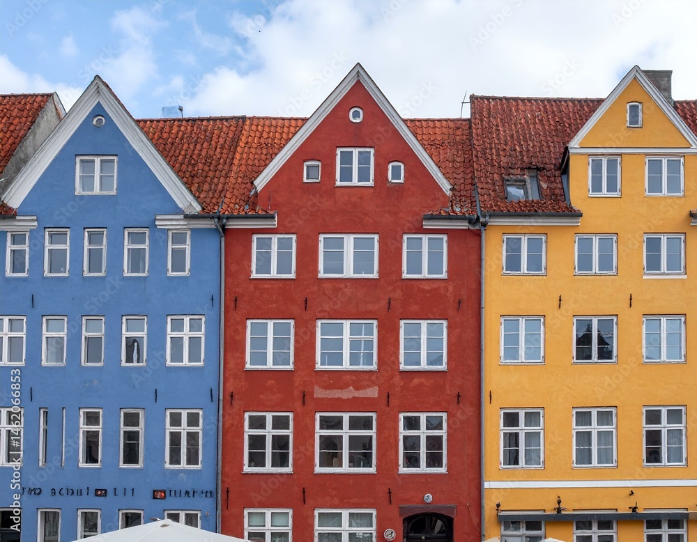 Three colorful European-style buildings with gabled roofs, red tile roofs, and many white windows under a cloudy sky. Three colorful European-style buildings with gabled roofs, red tile roofs, and many white windows under a cloudy sky.