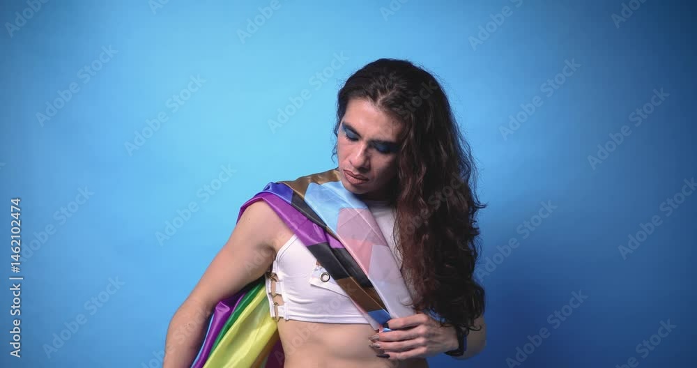 genderless person wrapped in a pride flag with a blue background and copy space genderless person wrapped in a pride flag with a blue background and copy space