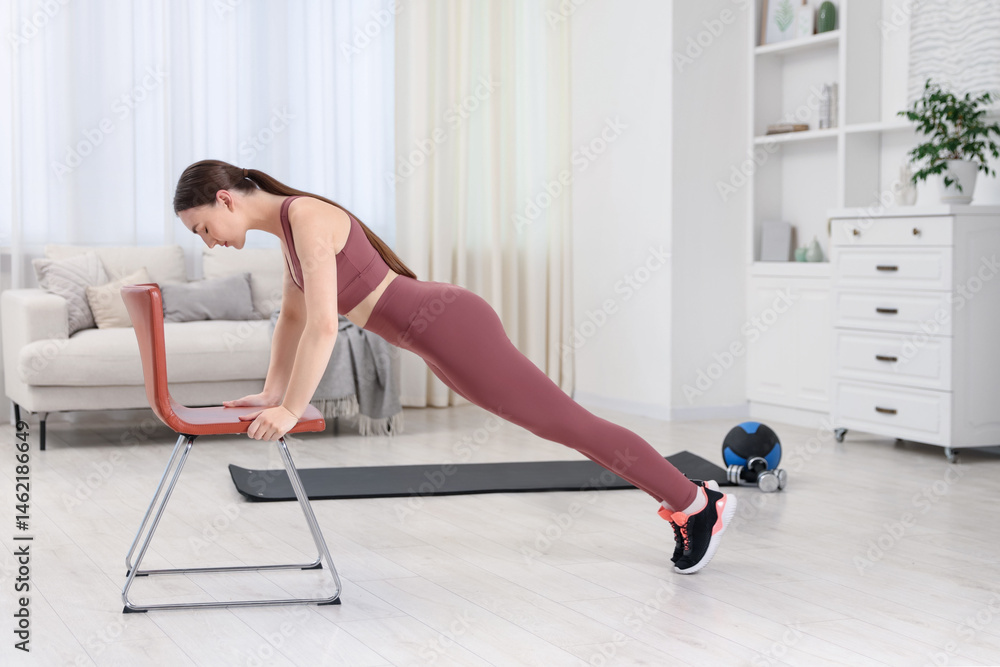 Obraz premium Beautiful woman exercising with chair at home