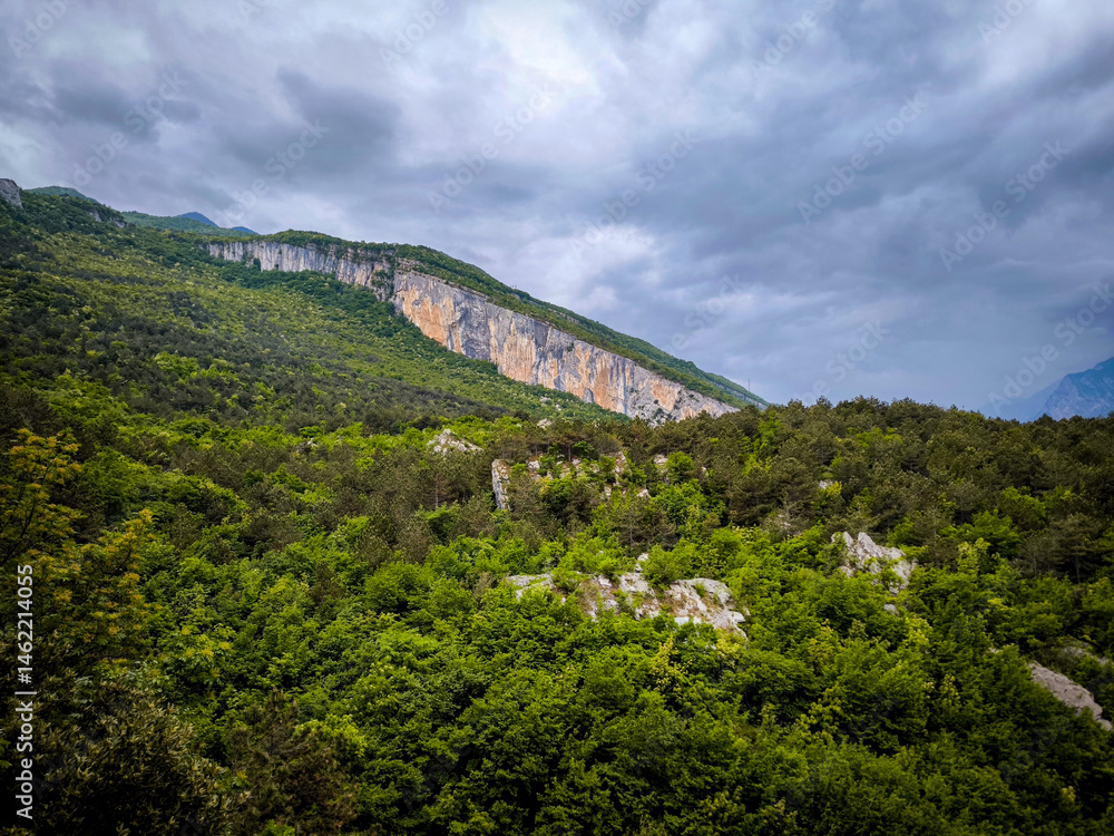 Obraz premium View From The Nago Climbing Base Camp In Italy, Overlooking Lush Green Forests And Rocky Cliffs