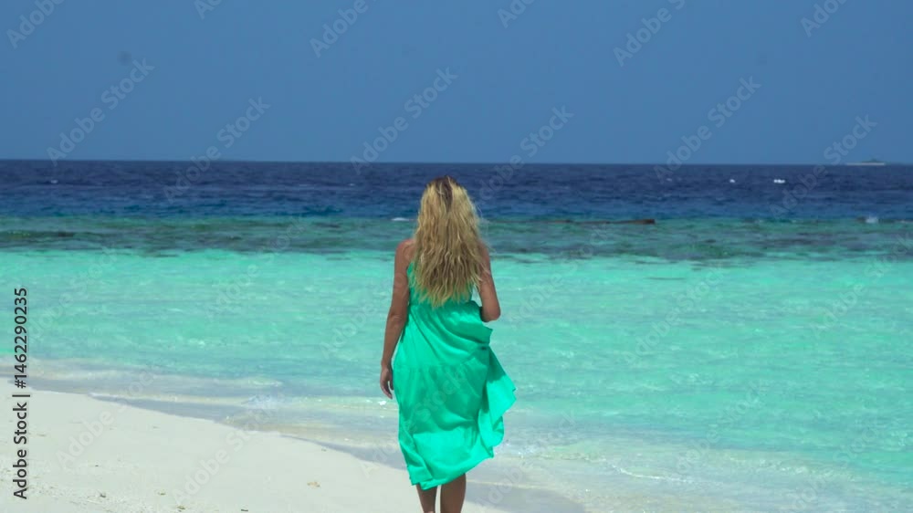 Woman walks along a beach in the Maldives, with turquoise waters and soft sand inviting her toward the horizon. Woman walks along a beach in the Maldives, with turquoise waters and soft sand inviting her toward the horizon.