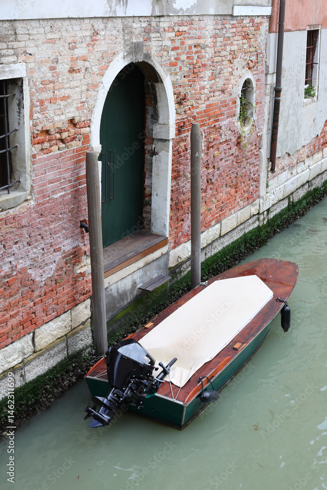 moored motorboat near the gate of the house in the navigable canal in Venice Island in Northern Italy