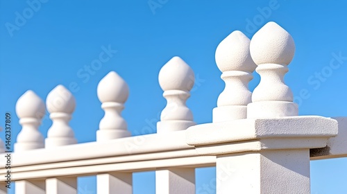 White fence with decorative finials against a clear blue sky